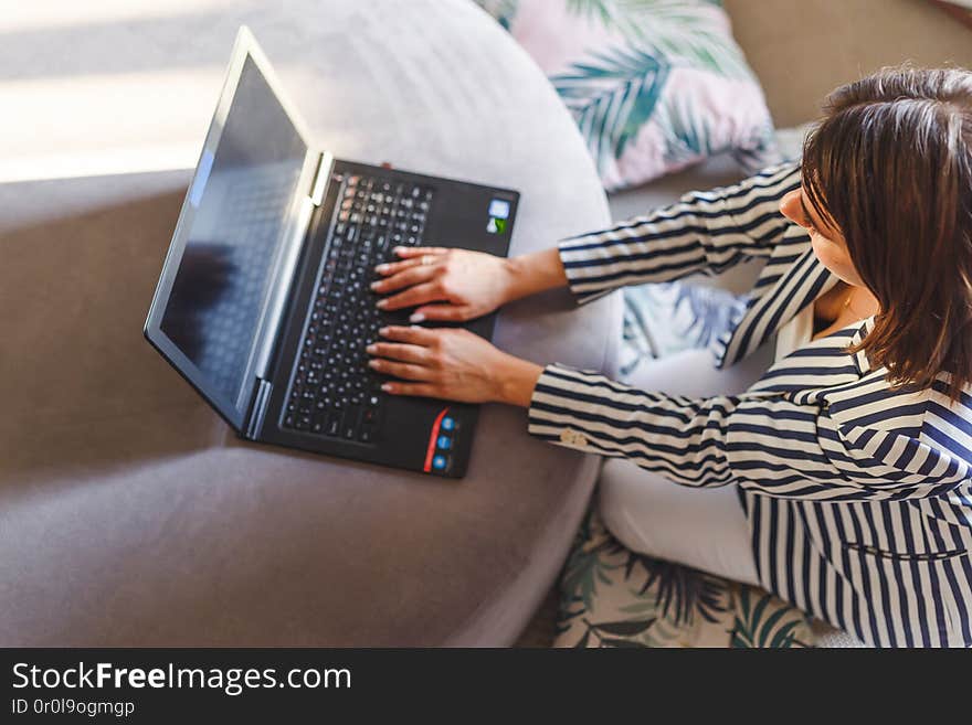 Top view of young woman sitting on floor with laptop.