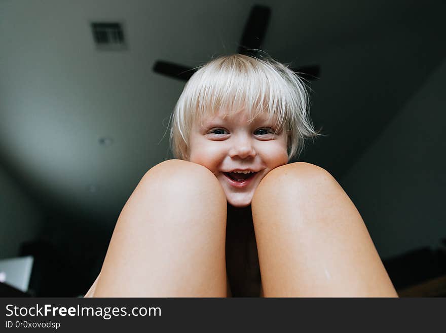 Adorable Cute Little Long Blonde Haired Blue Eyed Toddler Kid Boy Face Expressions Head Shots at Home Playing with Mom