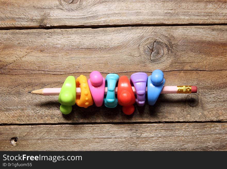 Pencils with Plastic Rings on Wooden Background