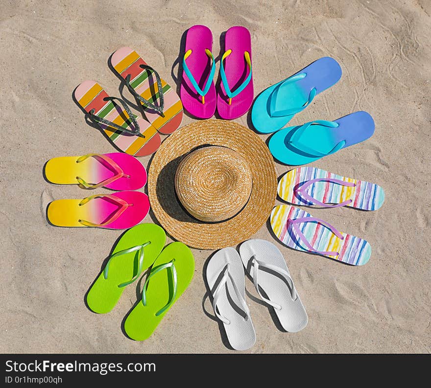 Flat lay composition with hat and flip flops on sand