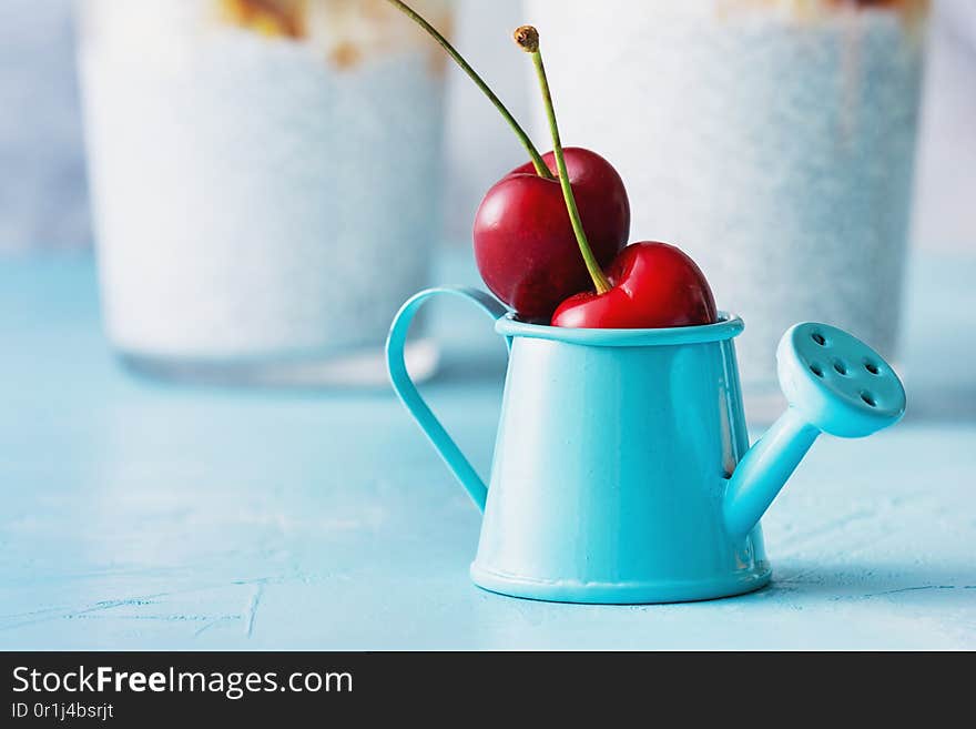 Mini Blue Watering Can with Two Ripe Cherry Fruit. Small Decorative Pot with Red Berry. Tiny Still Decoration with Fruity Ingredient. Natural Components for Diet Cocktail. Summer Garden Harvest