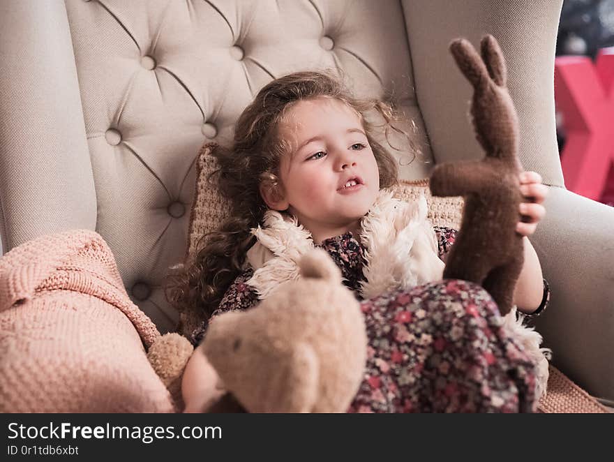 The little stylish girl plays with a hare. The warm winter atmosphere of heat and a cosiness in the house