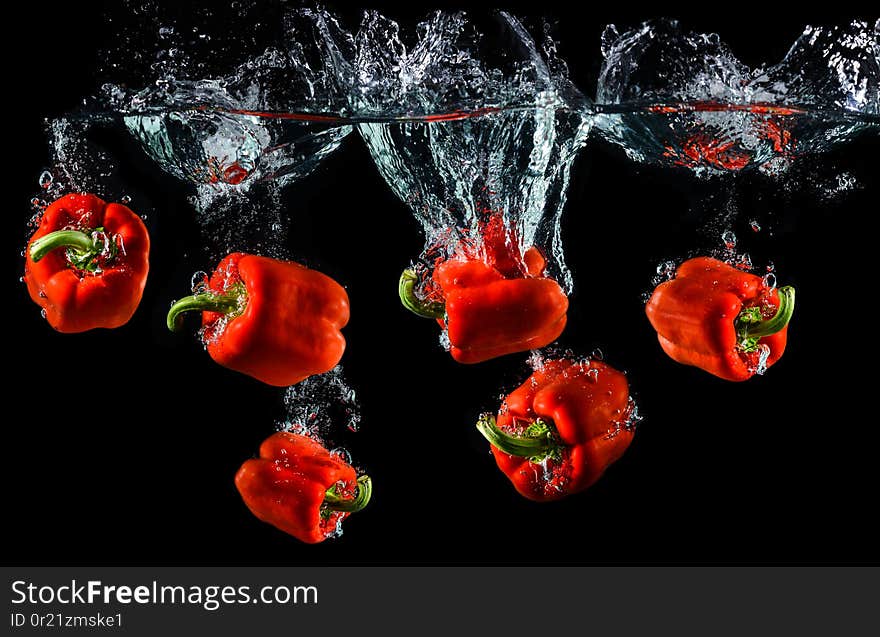 Water droping red bell pepper or paprika with splashing water in black background