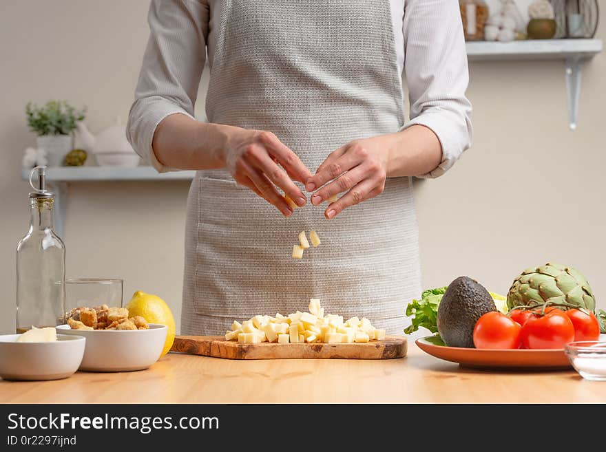 Cooking. A chef pours mozzarella or feta cheese, in the process of a vegetarian salad in the home kitchen. Light background. Restaurant menu, menu, recipe book. Healthy nutrition, detox...