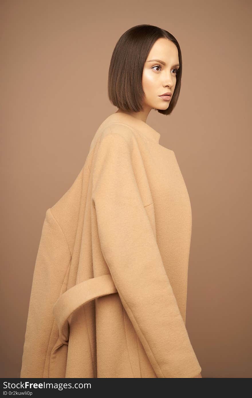 Fashion studio photo of young beautiful lady in beige coat on beige background. Total beige. Fashion look book. Warm Autumn. Warm Spring. Fashion studio photo of young beautiful lady in beige coat on beige background. Total beige. Fashion look book. Warm Autumn. Warm Spring