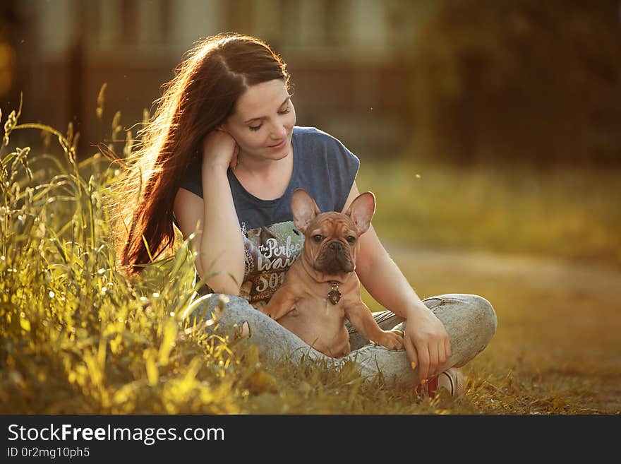 Young woman walking with a french bulldog puppy.