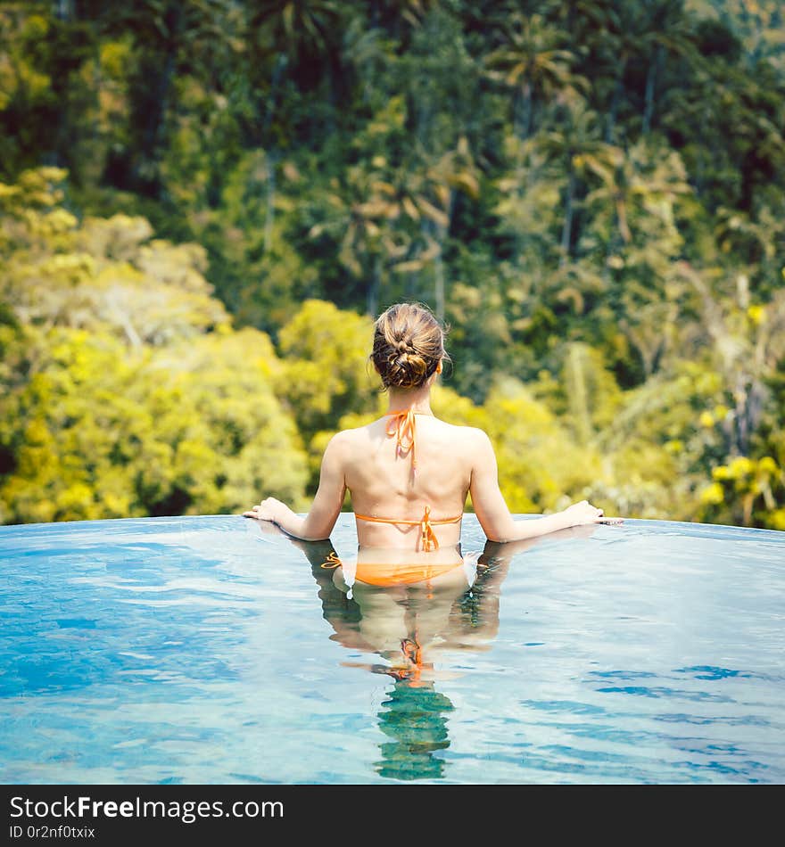 Woman in tropical vacation enjoying the jungle from the pool looking at the scenery