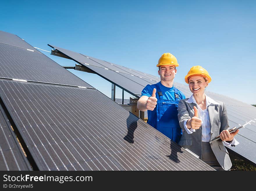 Worker and investor in solar power plant pointing at the sun