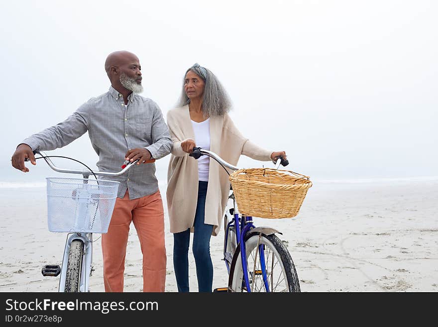 Couple Looking At Each Other While Holding Bicycles At The Beach