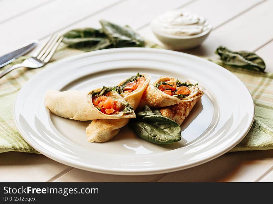 Rolls Of Thin Pancakes With Smoked Salmon, Horseradish Cream Cheese And Spinach Leaves. Side View With Copy Space