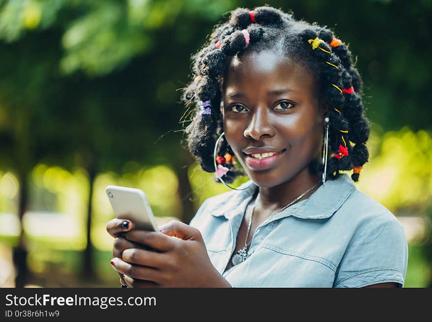 Portrait of a smiling young black woman in a park with sunlight flare and copy space. Portrait of a smiling young black woman in a park with sunlight flare and copy space