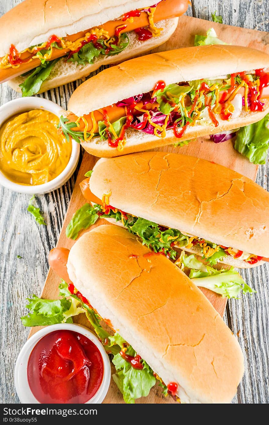 Homemade hot dogs with fresh greens, sausages and sauces, white wooden background copy space top view. Homemade hot dogs with fresh greens, sausages and sauces, white wooden background copy space top view