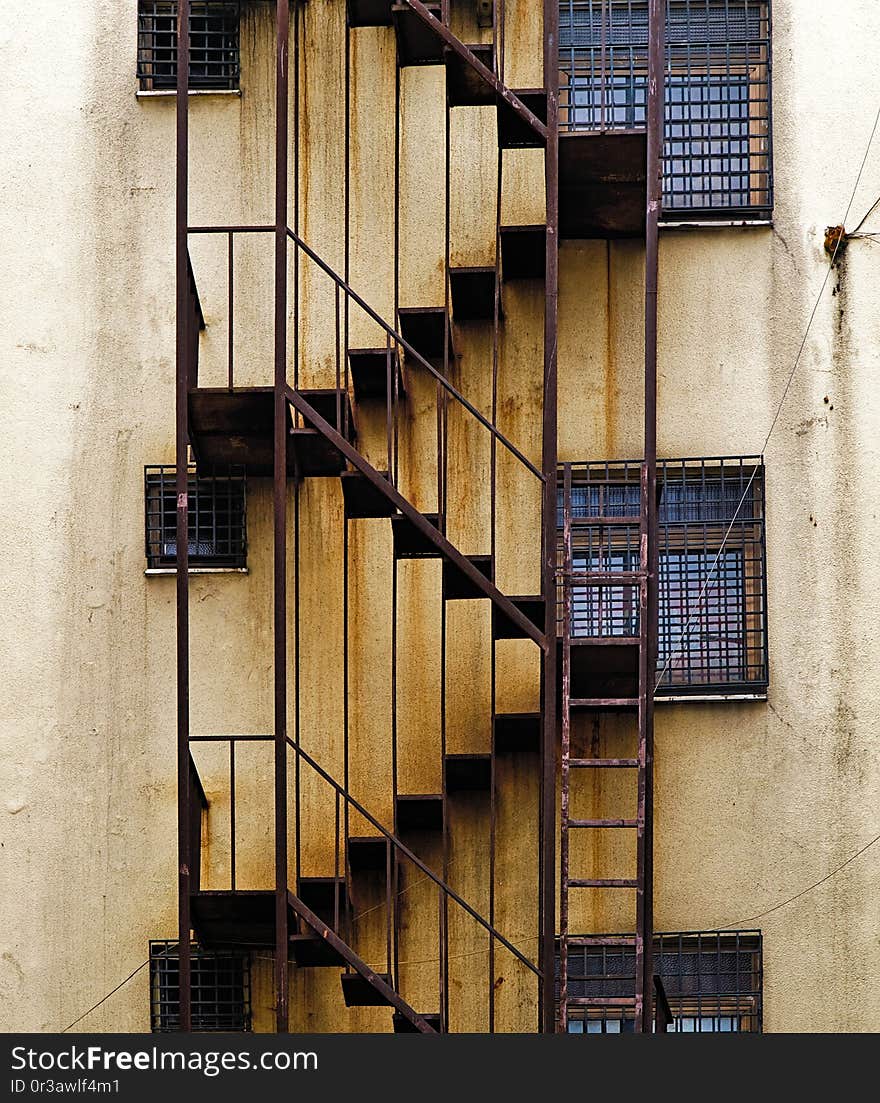 Urban building  back alley fire escape rusty stairs on aged wall. Urban building  back alley fire escape rusty stairs on aged wall