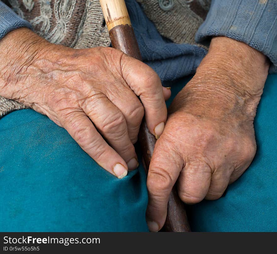 Hands of the old peasant woman. Holding the wooden walking stick