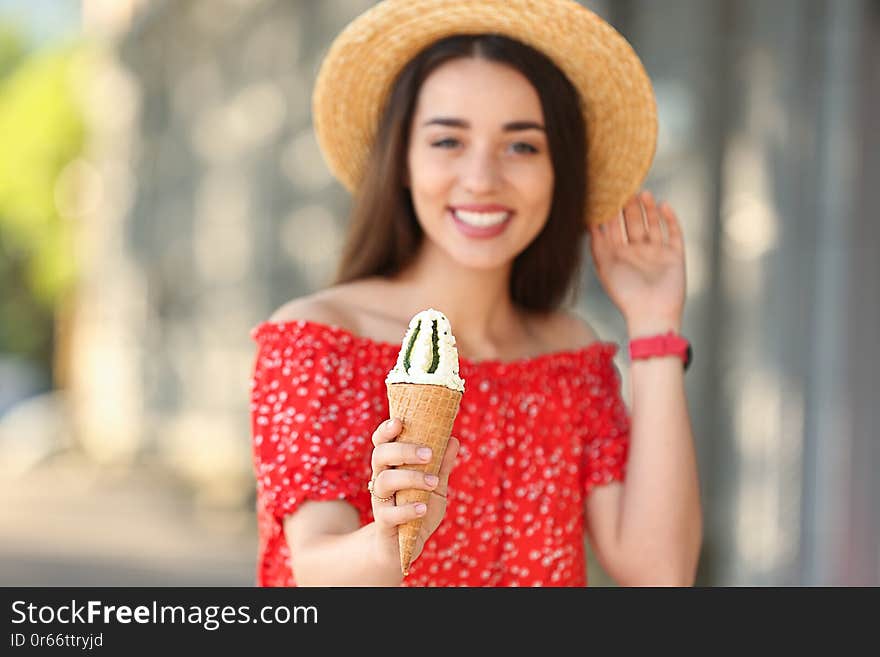 Happy young woman with delicious ice cream in waffle cone outdoors