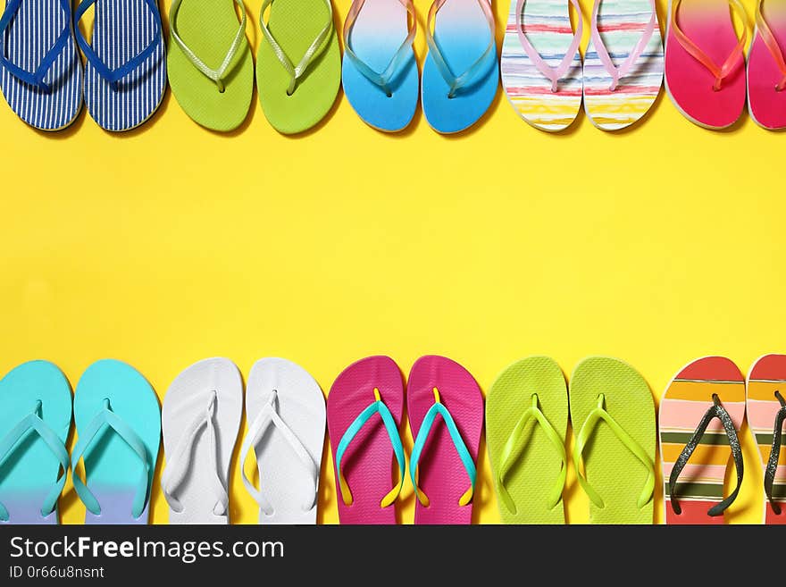 Different flip flops and space for text on yellow background, flat lay. Summer beach accessories