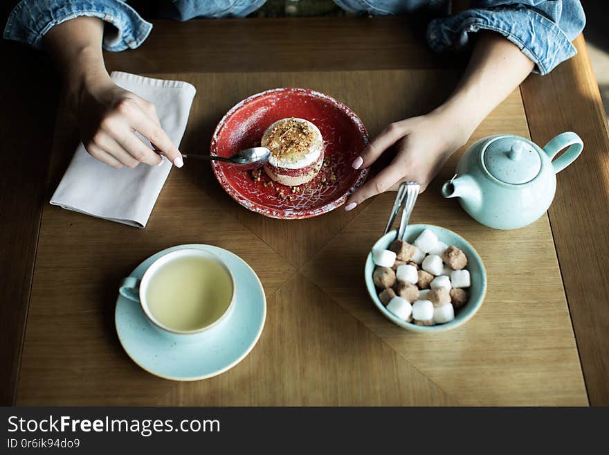 Young girl drinking tea with delicious dessert