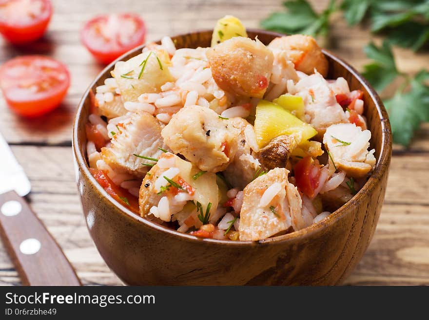 Stewed rice with chicken and vegetables in a wooden bowl,