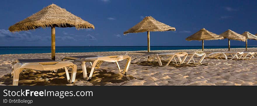 Panorama of empty sunbeds with umbrellas at night on the beach of Sal, Cabo Verde, Cape Verde. Panorama of empty sunbeds with umbrellas at night on the beach of Sal, Cabo Verde, Cape Verde