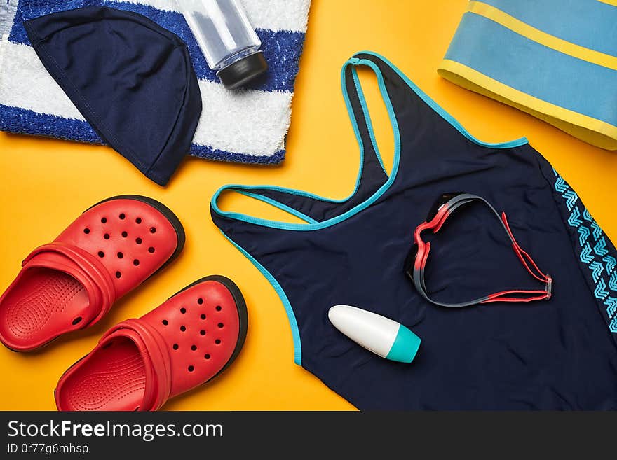 Flat lay summer pool accessories on a yellow background. Colorful beach wear.