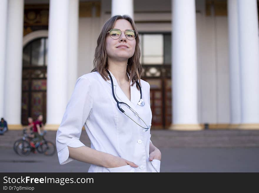 Young girl student at a medical university standing in the corridor, portrait of an attractive nurse near the hospital, happy