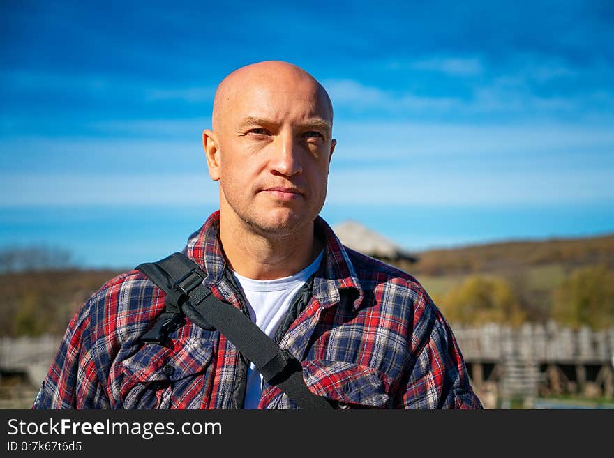 Portrait of a bald man against the sky and mountains.