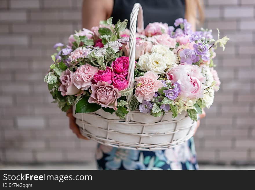 Flower arrangement in Wicker basket. Beautiful bouquet of mixed flowers in woman hand. Floral shop concept . Handsome fresh bouquet. Flowers delivery.