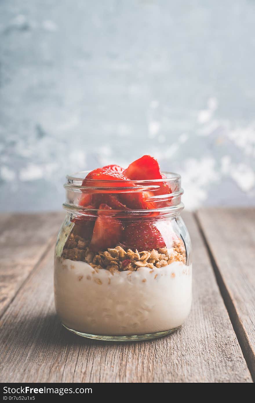 Healthy breakfast with yogurt, muesli and red ripe strawberry. Selective focus. Shallocw depth of field.