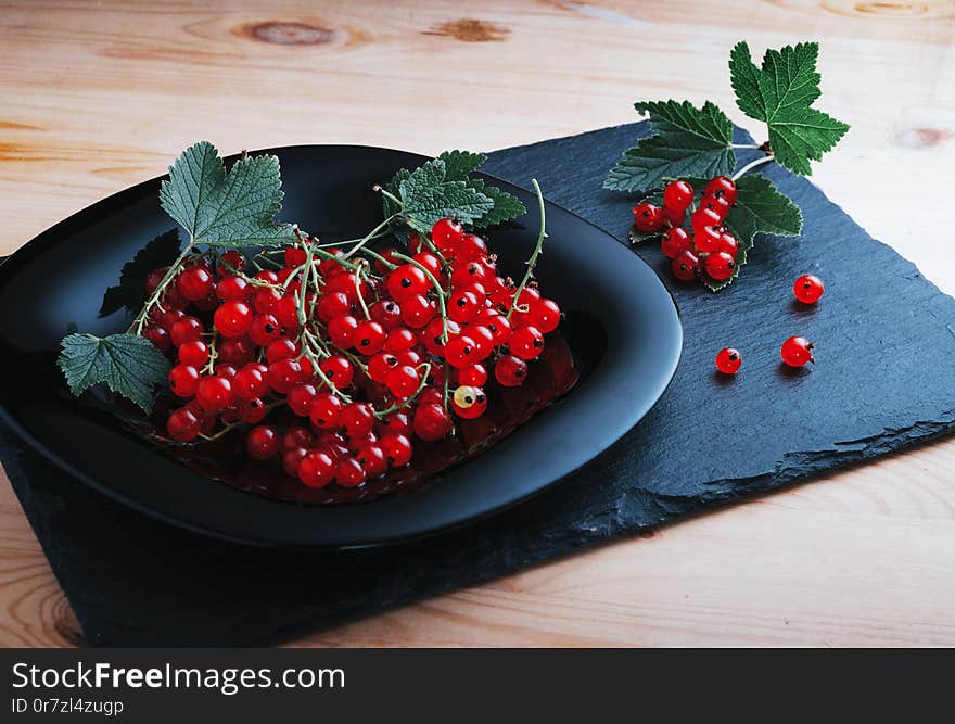 Redcurrants on a black plate on a wooden table