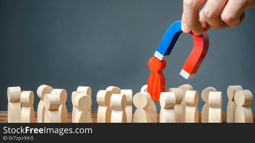 Businessman pulls out a red figure of a man from the crowd with the help of a magnet. leader manages the business and forms a team. toxic, incompetent worker. Increase team efficiency, productivity