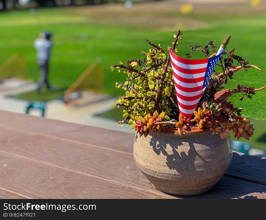 Patriotic flower pot with American flags and golfer on the background. American flag decoration.