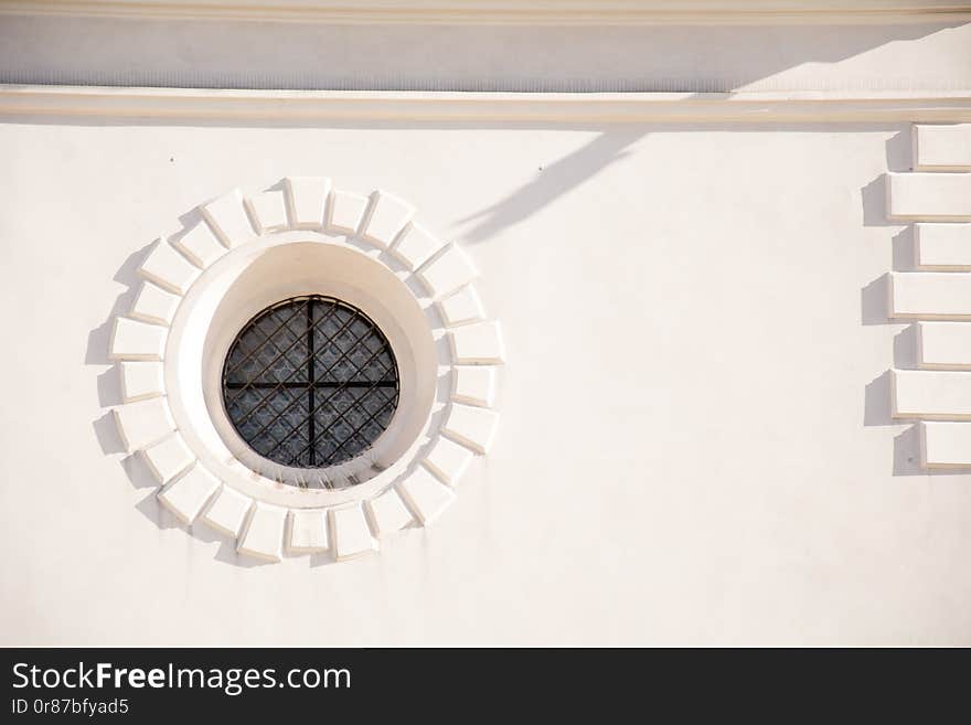 Beautiful round window on white wall of a house and shadow on it