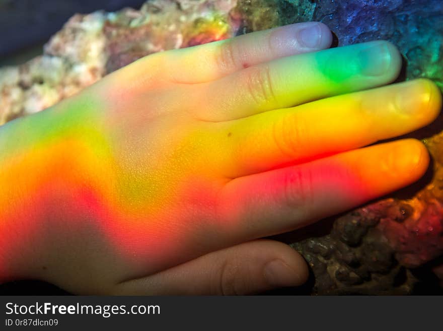 Rainbow colors are displayed on the baby`s hand.Reflection. Finger