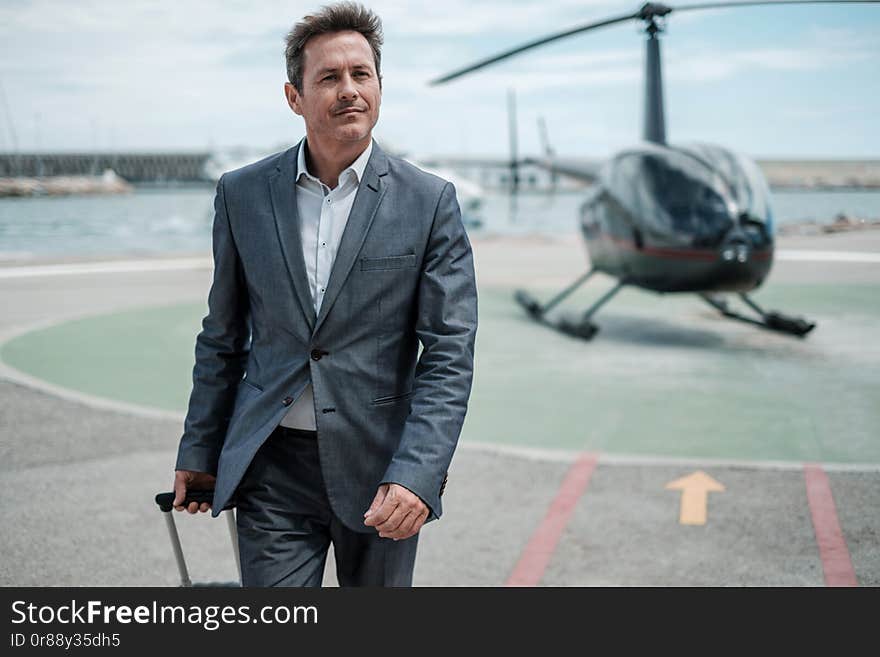 Businessman standing near private helicopter.