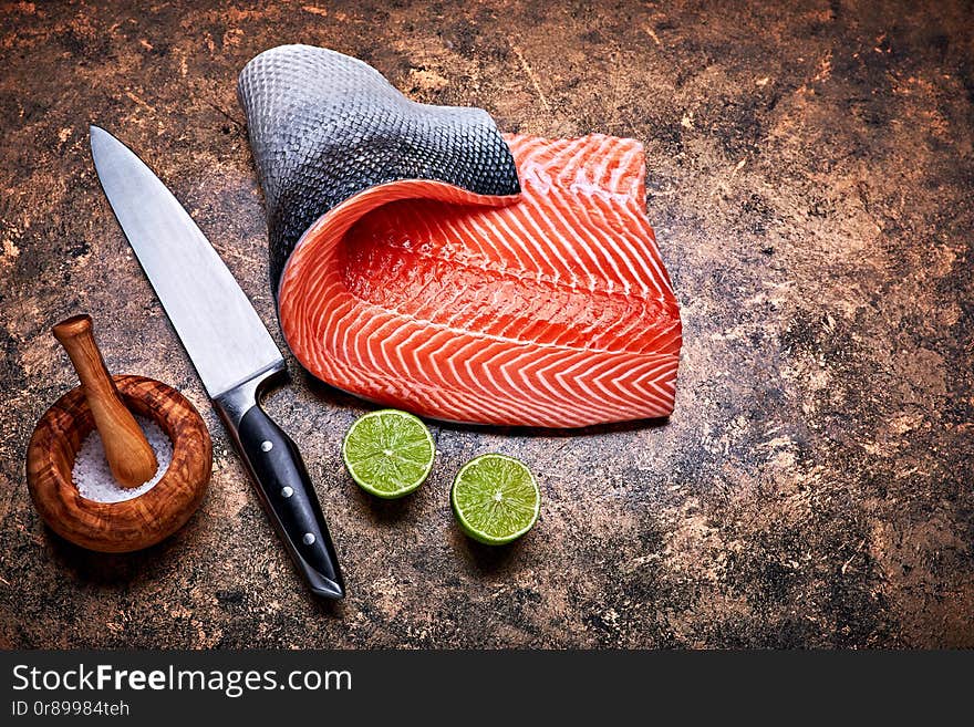 Fresh salmon steak red fish on grunge background with knife and cuted lime top view.