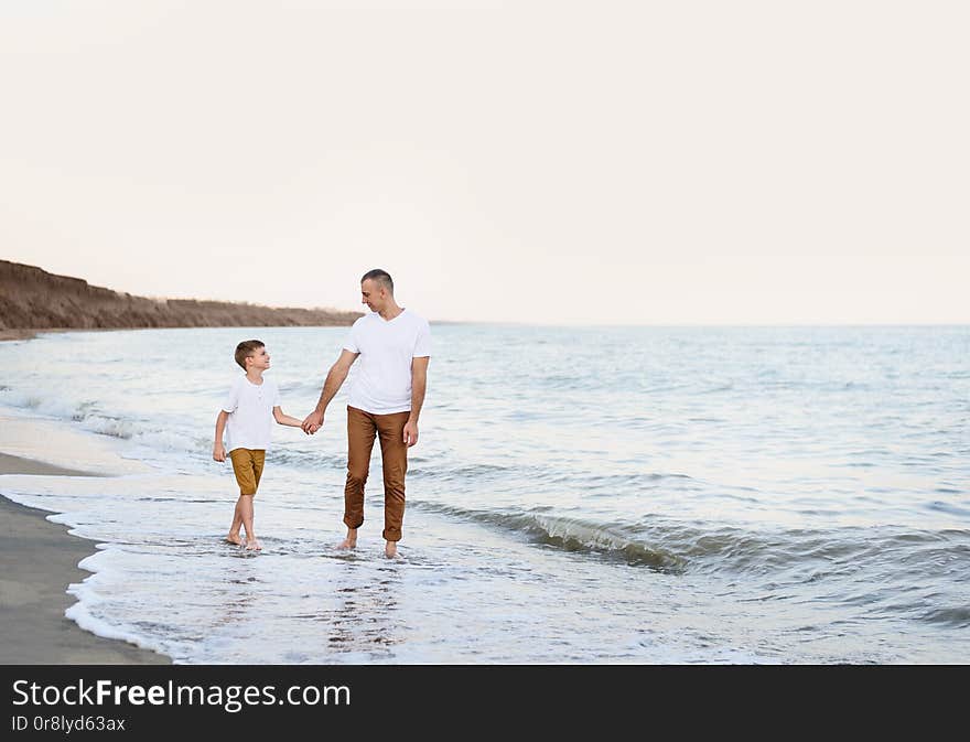 Father and son go by the hand along the sea coast. Family vacation. Friendship.