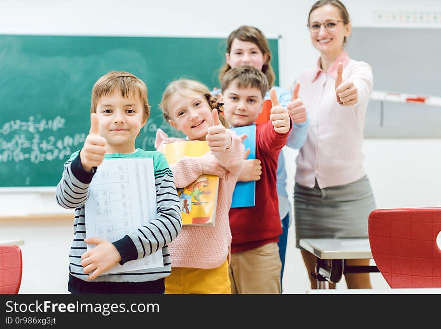 Pupils and teacher showing thumbs-up in school having fun