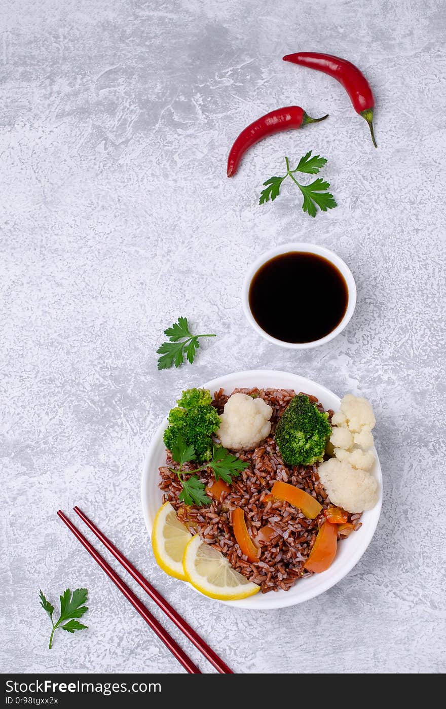 Unpolished red rice with vegetables in a ceramic dish on a slate background. Selective focus