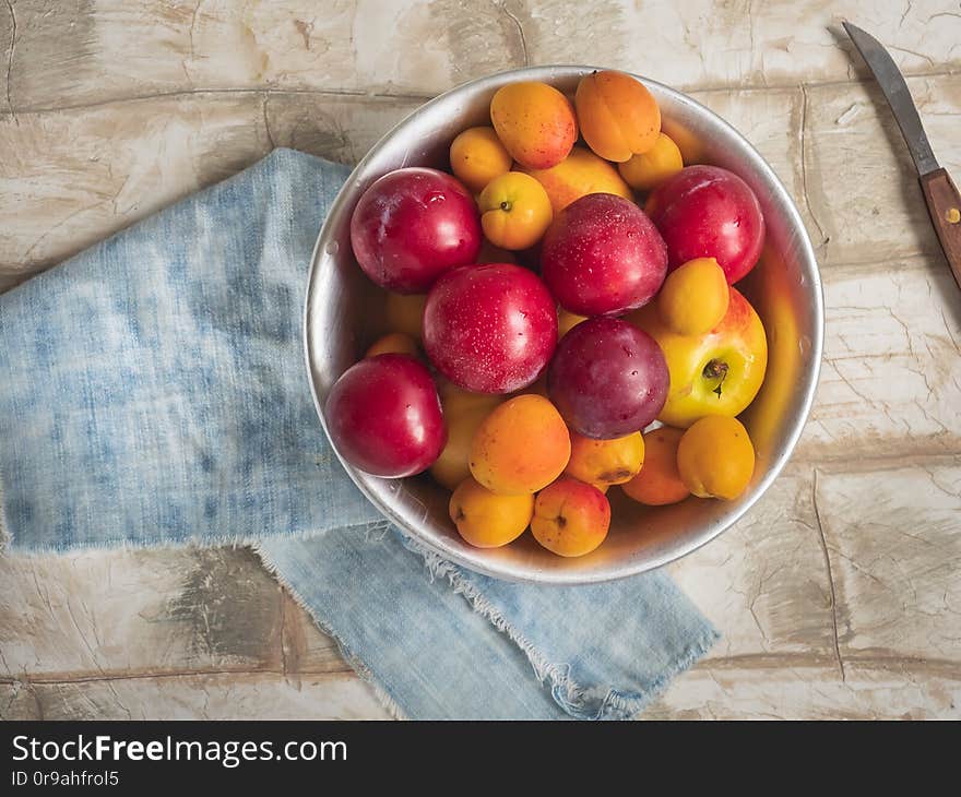 Fresh fruit nectarines, cream and apricots in a round plate on a denim napkin, the composition on a bright table