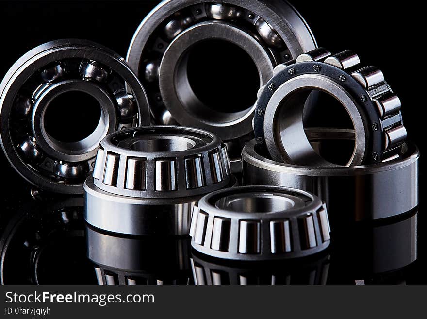 Close-up of a set of ball and roller bearings for repair lying on the desktop in the dark. Can be used as a background. Close-up of a set of ball and roller bearings for repair lying on the desktop in the dark. Can be used as a background