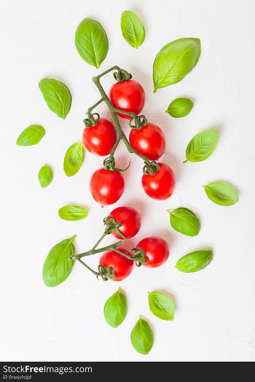 Organic Cherry Sugardrop Tomatoes on the Vine with basil and pepper on white kitchen stone background