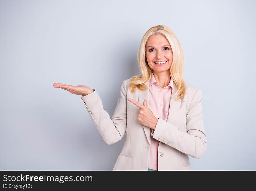 Portrait of her she nice-looking attractive lovely confident cheerful cheery, glad gray-haired lady holding copy space on palm ad advert isolated over light white gray pastel background. Portrait of her she nice-looking attractive lovely confident cheerful cheery, glad gray-haired lady holding copy space on palm ad advert isolated over light white gray pastel background