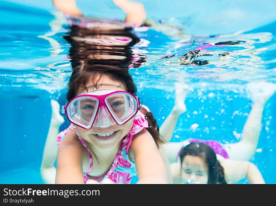 Little cute girl swimming underwater wearing goggles in resort