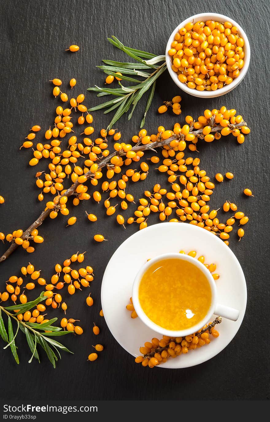 Sea buckthorn and cup of  tea on black stone table