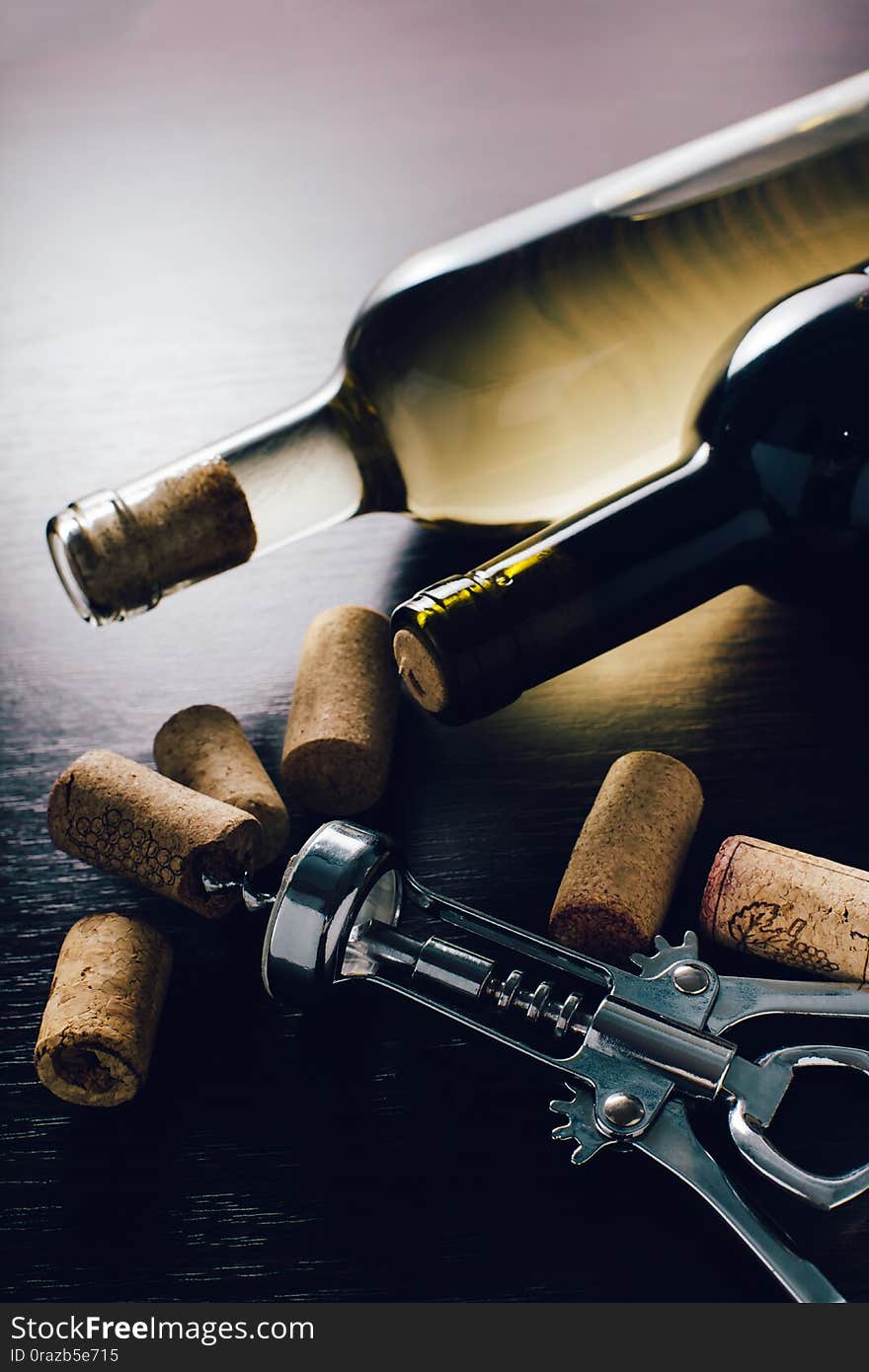 Bottles of wine and corkscrew on wooden background