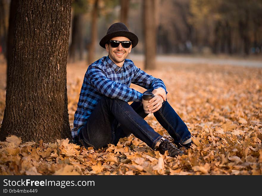 Young man wearing a check shirt and jeans walk in fall day