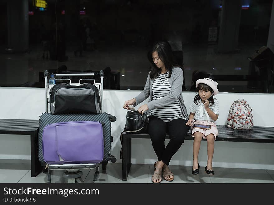 Asian pregnant woman and her daughter sitting in the waiting room airport