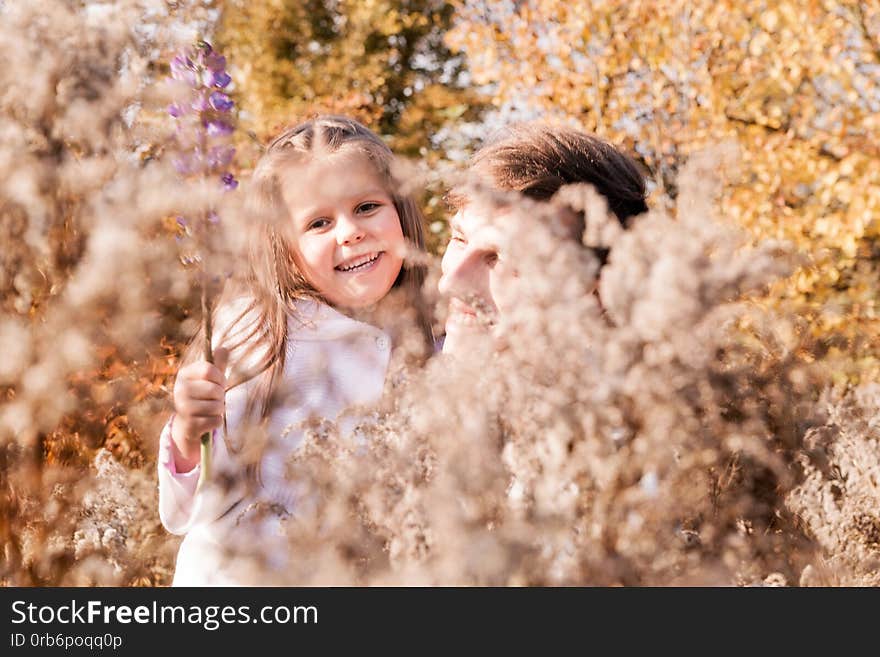 Happy dad and daughter posing among autumn yellow dry plants