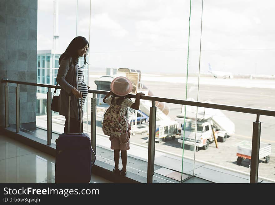 Happiness asian pregnant women and their daughter stand look a plane from the bigg glass windows