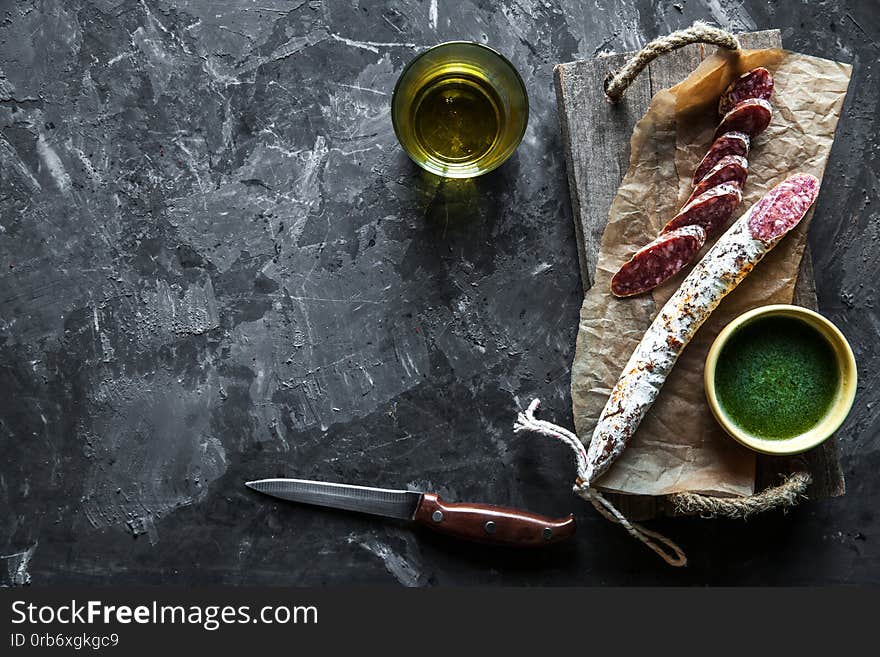 Sausage on a dark background with elements of cooking. Cucumber, onion, ketchup